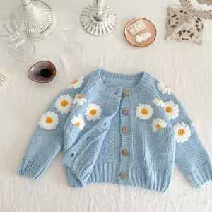 Infant blue knit cardigan featuring white daisy embroidery and wooden buttons. Detail view.