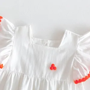 Cute white baby dress detail with orange pom pom trim, sweet infant summer princess outfit.