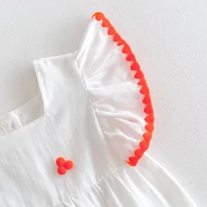 Baby girl white dress sleeve detail with vibrant orange ruffles and cute pom poms trim summer style