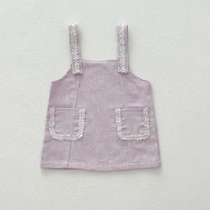 Robe chasuble bébé fille en tweed rose avec bordures frangées colorées. Vue de détail.