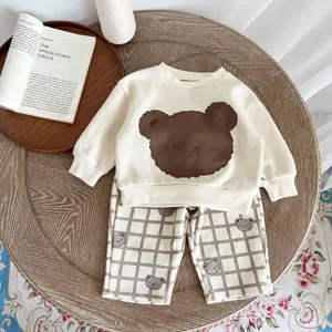 Vista detallada de sudadera infantil y pantalón con estampado de oso, algodón suave.