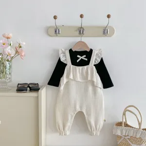 Detailed shot of infant ribbed romper and top set, hanging on wall hook with minimalist decor.