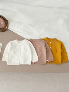 Infant knitted cardigan detail view, showing soft cotton fabric texture, cute buttons and weave.