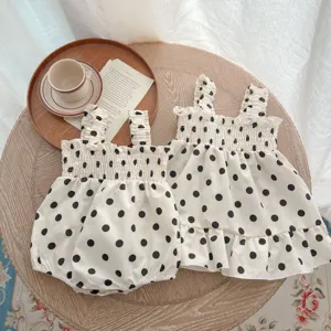 Gedetailleerd overzicht van de zomer polka dot baby romper en jurk set op houten tafel.