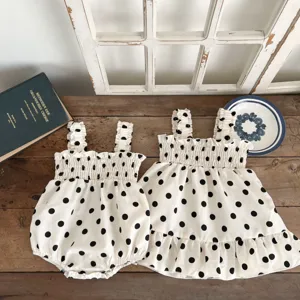 Gedetailleerd uitzicht op een schattige zomerse rompertje en jurk set met stipjes voor baby.