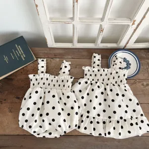 Gedetailleerd overzicht van baby stipjes romper en jurk set met leuke volants op hout.