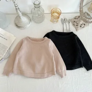 Detaillierte Flat-Lay-Aufnahme kuscheliger Kleinkind-Strickpullis auf weißer Texturoberfläche.