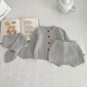 Detalle del elegante conjunto de suéter de punto para bebé en gris con bufanda a juego.