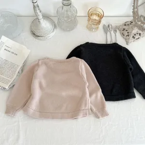 Detailansicht süßer Babypullover aus Strick in Rosa und Dunkelgrau, weiche Textur.