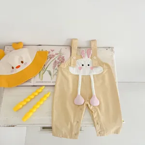 Close-up detail of cute baby girl yellow overalls featuring 3D cartoon bunny plush applique.