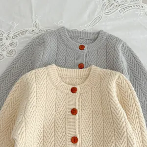 Cardigan de punto para bebé vista de detalle, acogedor patrón de trenzas, botones.