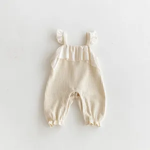 Detailed shot of baby ribbed romper with ruffled straps and embroidered chest frill.