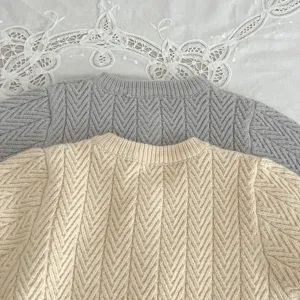 Detalle de jersey de punto para bebé, patrón chevron suave parte superior gris y beige.