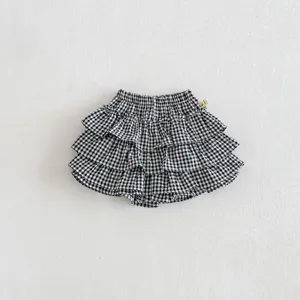 Detailed shot of infant black white plaid layered skirt with ruffles and elastic waist.