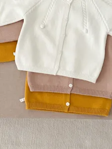 Infant knit cardigan detail, soft cotton solid color baby sweater jacket layers for autumn.