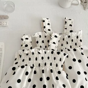 Gedetailleerd overzicht van de witte baby jurk met zwarte stippen en leuke volants.