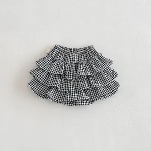 Detailed view of infant black and white plaid tiered ruffle skirt with elastic waist.