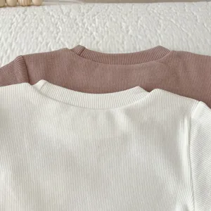Close-up detail of soft ribbed cotton baby t-shirt in white and mauve, comfortable daily wear.