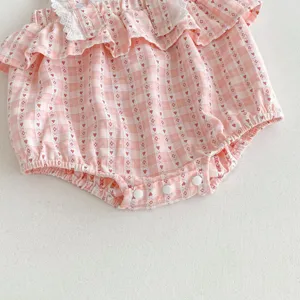 Dettaglio ravvicinato della tutina neonata a quadri rosa con colletto in pizzo e cuori.