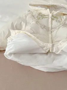 Detailaufnahme des wattierten Babyeinteilers, niedliche Spitzenstickerei und weiches Futter.