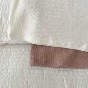 Detailed view of soft cotton ribbed fabric in white and pink, perfect for children clothing.