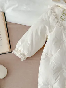 Nahaufnahme des gefütterten Baby Winter Jumpsuits mit süßen Stickereien und Spitzenkragen.