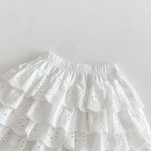 White eyelet tiered ruffle skirt detail showing delicate embroidery and elastic waistband close-up.