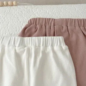 Close-up detail of children's solid color ribbed elastic waist trousers in soft cotton fabric.