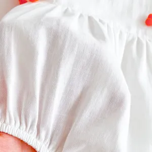 Newborn baby girl white romper dress detail close-up, soft breathable summer infant clothing.