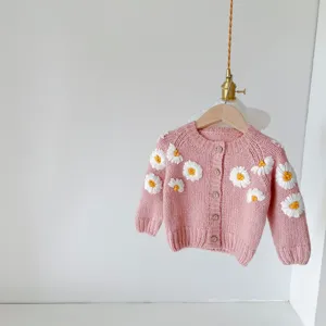 Detailed view of handmade daisy embroidered baby pink knit cardigan sweater with cute buttons.