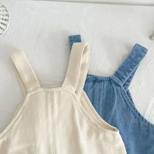 Cute infant baby girl denim bib pants detail view, stylish autumn cotton toddler overalls.