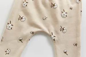 Babyhosen Detailansicht mit süßem Baumwollblumen Print auf weichem beigen Stoff.