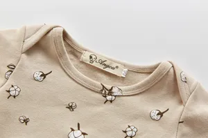 Detailaufnahme des Babystrampler-Ausschnitts mit Blumenmuster und kleiner Marken-Kragenetikette.