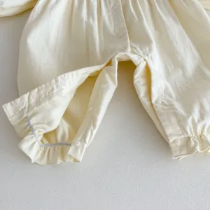 Dettaglio primo piano bottoni pressione cavallo tutina neonato cotone, tessuto beige.