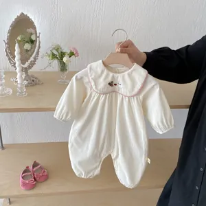 Vue détaillée de la combinaison bébé fille à manches longues, velours côtelé blanc et col rose.