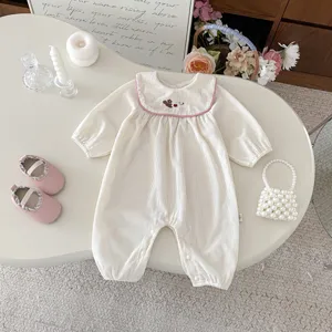 Adorable barboteuse à manches longues pour bébé avec col claudine et broderie délicate.