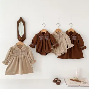Detailed display of lovely corduroy baby rompers and dresses hanging in a cozy room setting.