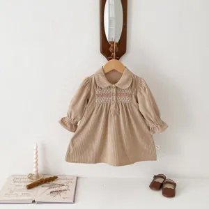 Detailed view of the cute corduroy baby dress featuring delicate smocked embroidery and collar.