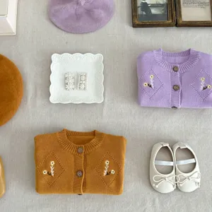 Detailed flat lay of toddler knit cardigan, cute hair clips, beret and shoes for little girls.