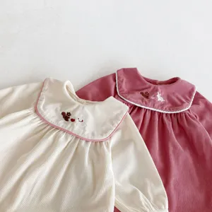 Vue détaillée de la combinaison bébé en velours côtelé avec broderie et manches longues.