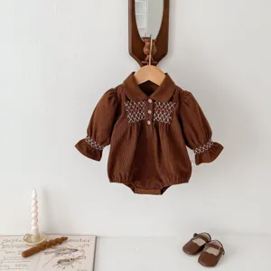 Detailed view of brown corduroy baby romper featuring cute white embroidery and collar.