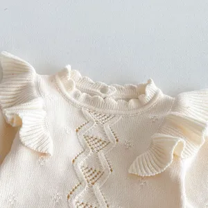 Baby knit sweater detail, cute cream pullover with ruffles and hollow-out diamond pattern.