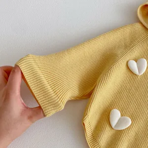 Close-up detail of toddlers spring knitted sweater cuff, showing soft texture and cute heart.