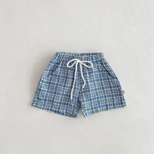 Gros plan sur le short de bébé à carreaux bleu et blanc avec cordon blanc et tissu doux.