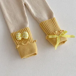 Cute toddler girls knit leggings detail with yellow ribbed cuffs and checkered bows.