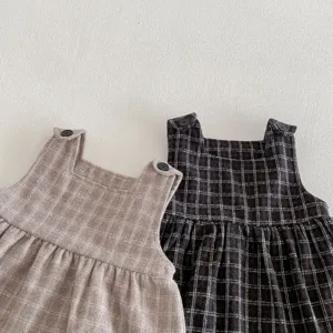 Dettaglio dell'abito scamiciato in tweed a quadri per bambina con bottoni sulle spalle.