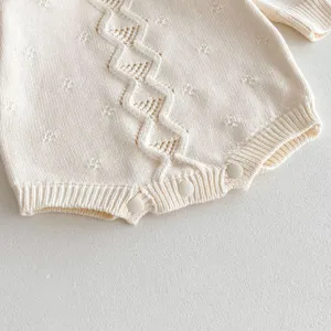 Baby cream knitted romper with zigzag pattern detail, soft cotton infant clothing.