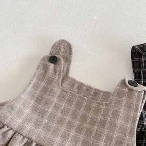Dettaglio di abito in tweed a quadri per bambina con tessuto marrone e bottoni neri.