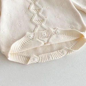 Close-up shot showing delicate knit texture and button detail of baby knitted romper item.