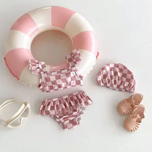Détail de maillot de bain pour tout-petit à carreaux roses, joli vêtement de bain avec bonnet.